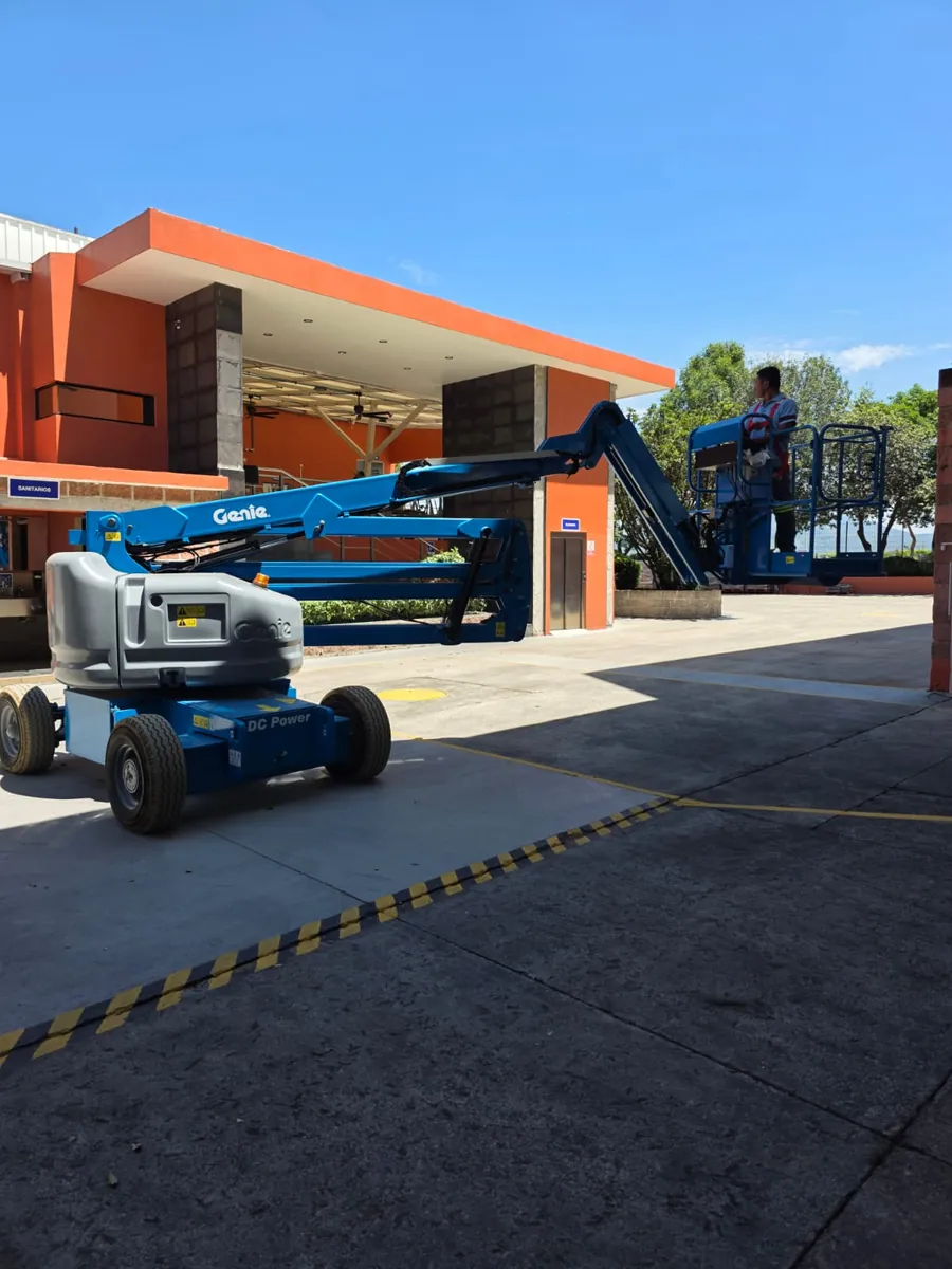 Plataforma de elevación articulada con la canastilla extendida y un operador a bordo, al aire libre